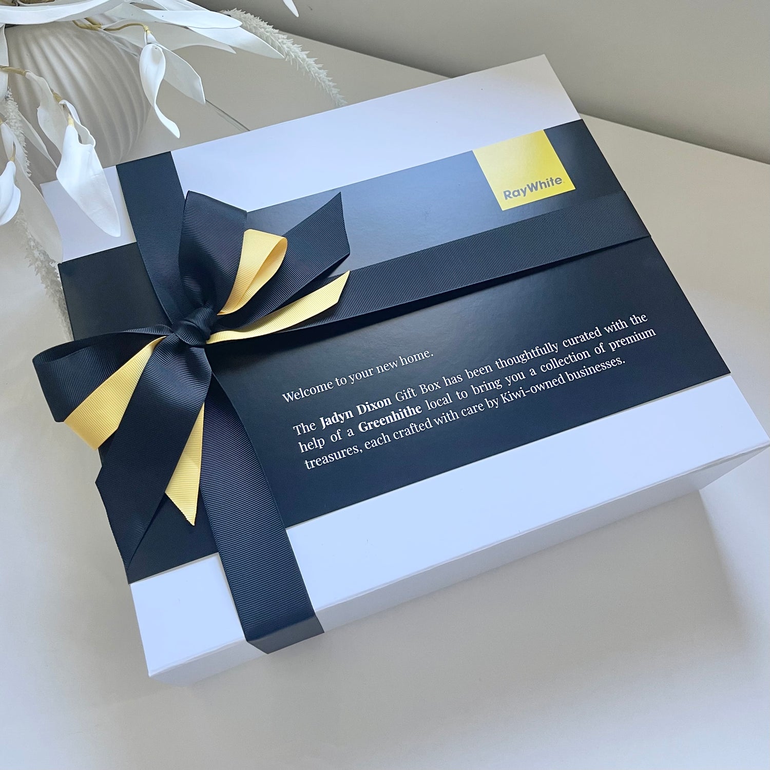 Gift box with a black and gold ribbon on a light background. Real Estate agents closing gifts