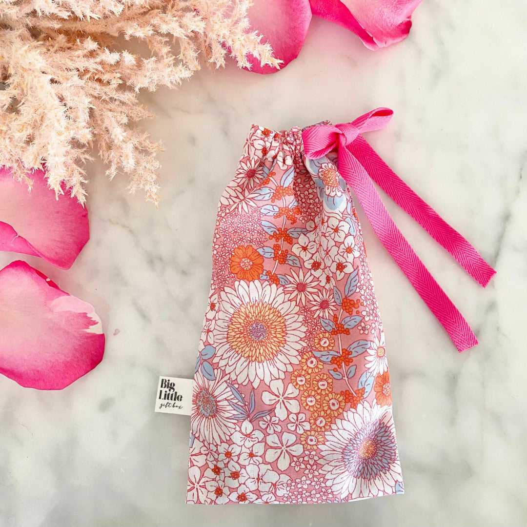 Gift bags NZ | Drawstring bags | New Zealand made products | Reusable bag | A cute little drawstring bag which is the perfect size for sunglasses, make-up, pens and pencils or pair with a matching keychain to store your car keys. Made from a pink floral fabric with bright pink drawstrings.